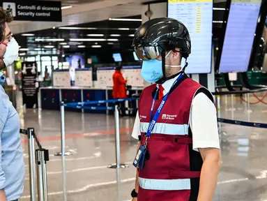 Petugas mengenakan termoscanner portabel "Smart-Helmet" untuk memeriksa suhu penumpang dan sesama staf di terminal keberangkatan bandara Fiumicino Roma, Italia pada 5 Mei 2020. Hal ini dilakukan guna menyaring orang yang memiliki gejala infeksi virus corona. (ANDREAS SOLARO/AFP)