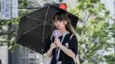 Seorang wanita menggunakan payung untuk berlindung dari sinar matahari saat berjalan di sepanjang jalan di Tokyo pada 19 September 2024. (Yuichi YAMAZAKI/AFP)