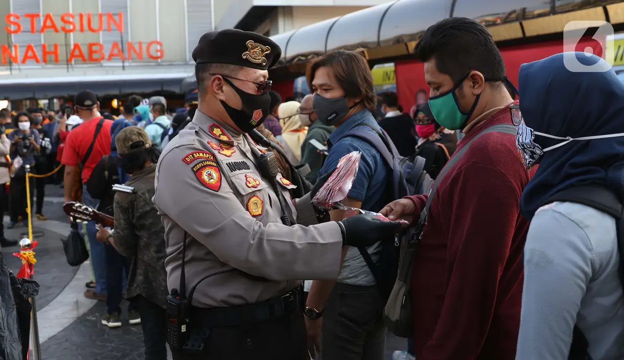 Personel polisi membagikan masker kepada calon penumpang kereta di area pedestrian Stasiun Terpadu Tanah Abang, Jakarta, Kamis (27/8/2020). Guna menekan penyebaran Covid-19, Polda Metro Jaya dan Kodam Jaya terus mengampanyekan pentingnya menaati protokol kesehatan. (Liputan6.com/Helmi Fithriansyah)