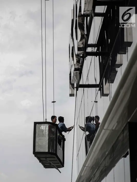 Pekerja naik gondola tanpa helm keselamatan beraktivitas di gedung bertingkat di Jakarta, Rabu (15/11). Banyak kejadian kecelakaan kerja di ketinggian disebabkan karena mahalnya peralatan pengaman pribadi yang ada di pasaran. (Liputan6.com/Faizal Fanani)