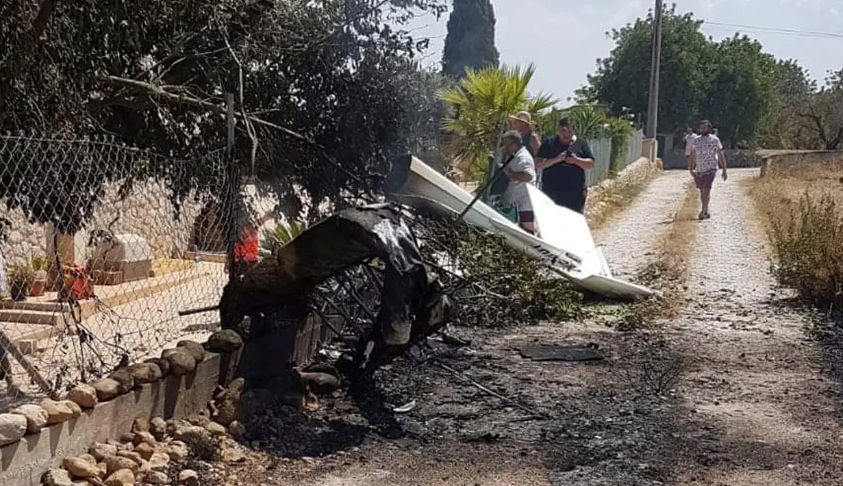 Puing-puing bekas tabrakan antara sebuah helikopter dan pesawat kecil terlihat di jalan dekat Mallorca, Spanyol, Minggu (26/8/2019). Setidaknya tujuh orang tewas, termasuk dua anak di bawah umur, dalam insiden tabrakan udara tersebut. (Incendios f.Baleares via AP)