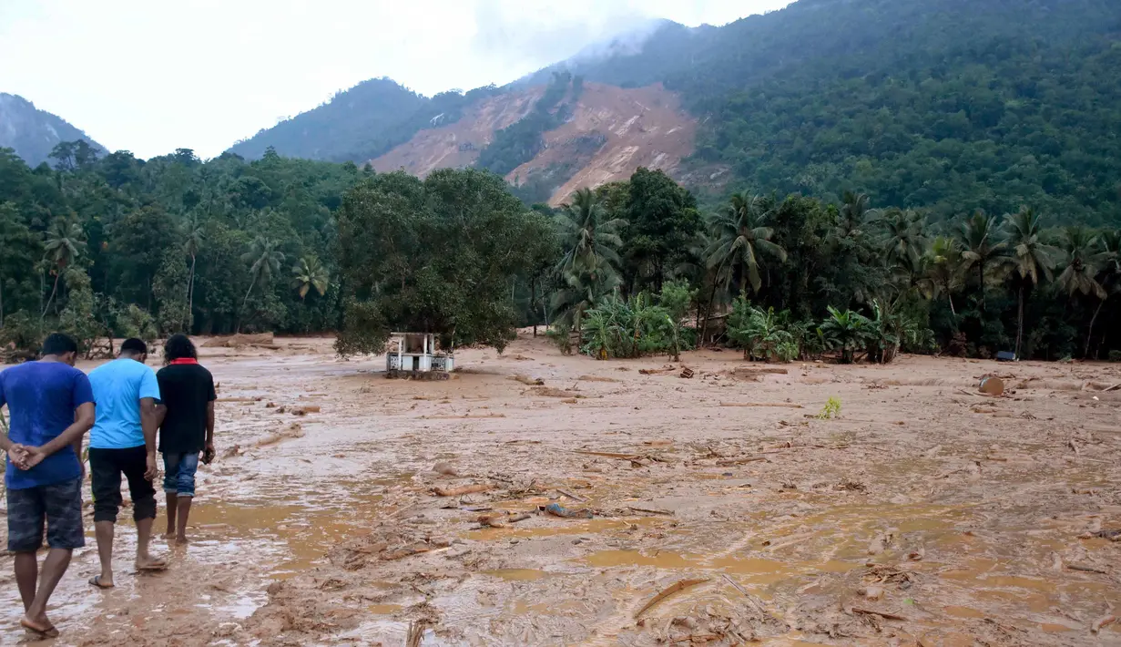 Sejumlah berjalan melintasi salah satu wilayah pemukiman yang terkena longsor di Desa Elangipitiya, Aranayaka, Sri Lanka (19/5). Bencana tanah longsor disebabkan oleh hujan lebat selama berhari-hari di Sri Lanka. (REUTERS/Dinuka Liyanawatte)