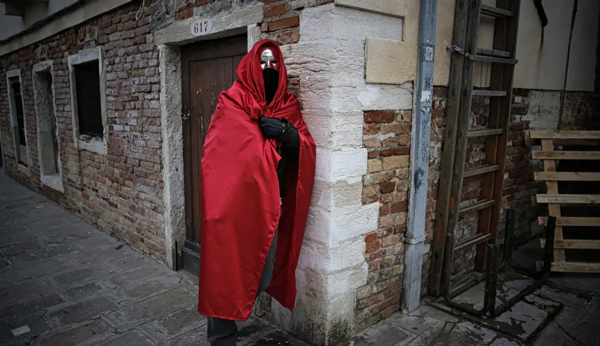 Seorang pria mengenakan kostum dan topeng bersiap mengikuti pembukaan Carnival of Venice 2017, Italia (11/2). (AFP/Marco Bertorello)