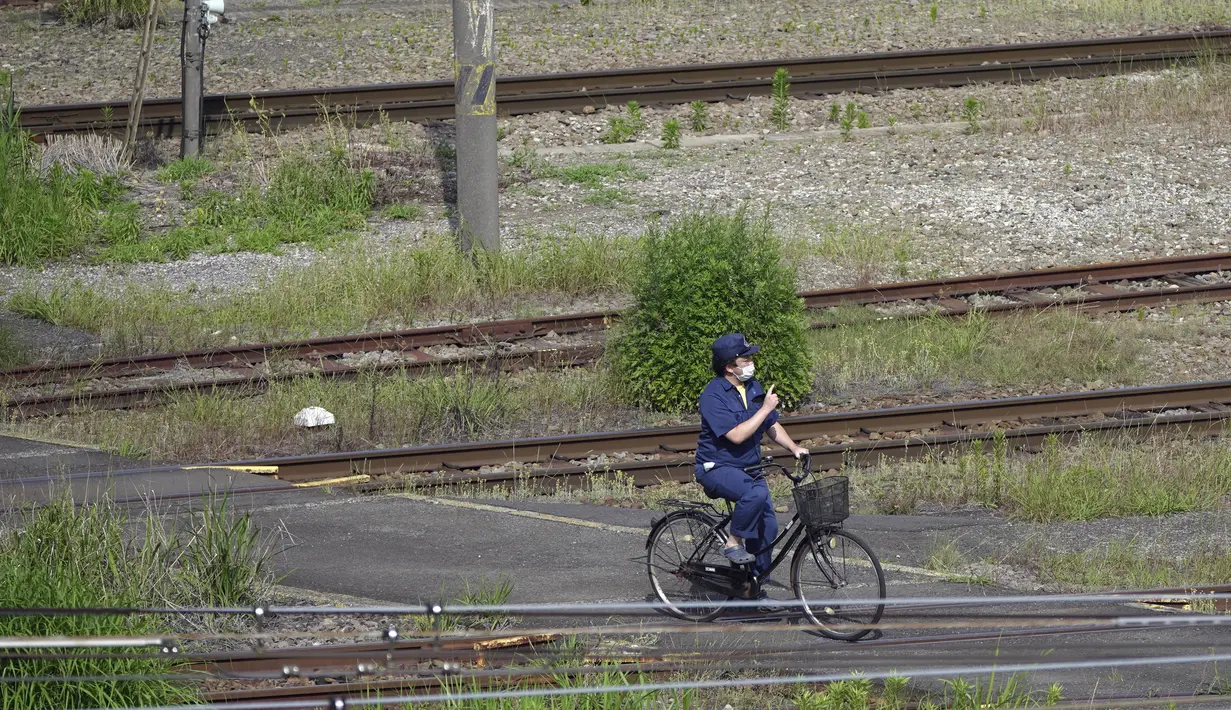 <p>Seorang staf kereta api mengendarai sepeda di bawah terik matahari di Tokyo, Senin (30/5/2022). Cuaca panas pada hari Senin telah ditetapkan dengan suhu naik lebih dari 27 derajat Celcius (80,6 derajat Fahrenheit) di Tokyo, menurut Badan Meteorologi Jepang. (AP Photo/Eugene Hoshiko)</p>