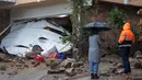 Orang-orang berdiri di dekat garasi yang diterjang tanah longsor dan banjir bandang di lingkungan perumahan, California, pada 5 Februari 2024. (DAVID MCNEW/AFP)