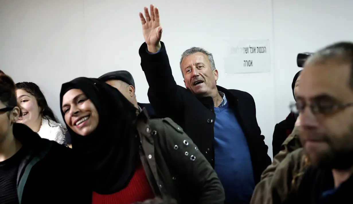 Ayah Ahed Tamimi, Bassem Tamimi mengangkat tangannya memberi dukungan kepada putrinya saat berada di pengadilan militer Israel di penjara Ofer, Israel (13/2). (AFP/Thomas Coex)