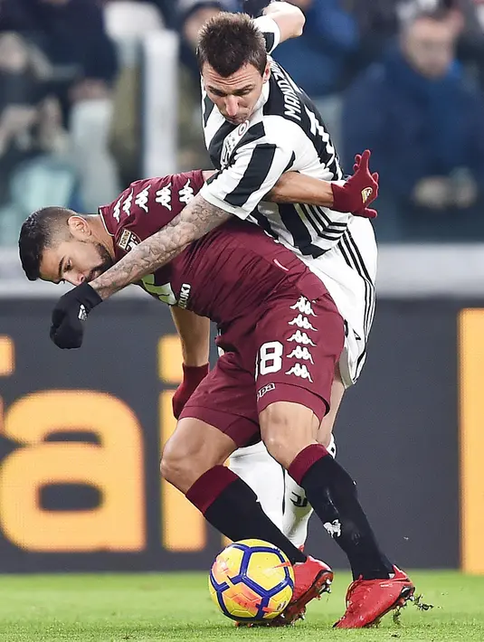 Pemain Juventus, Mario Mandzukic berebut bola dengan pemain Torino, Tomas Rincon dalam lanjutan Coppa Italia di Stadion Allianz, Rabu (3/1). Juventus menang dengan skor akhir 2-0 atas klub sekota mereka, Torino. (Andrea Di Marco/ANSA via AP)