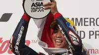 Pebalap Indonesia binaan Astra Honda Racing Team (AHRT), Gerry Salim, mengangkat trofi juara di podium setelah memenangi balapan pertama Asian Talent Cup (ATC) 2016 Qatar di Sirkuit Losail, Sabtu (19/3/2016). (asiatalentcup.com)
