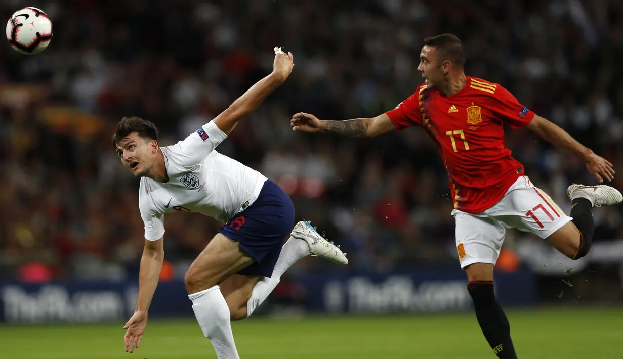 Striker Spanyol, Iago Aspas, berebut bola dengan bek Inggris, Harry Maguire, pada laga UEFA Nation League di Stadion Wembley, London, Sabtu (8/9/2018). Inggris kalah 1-2 dari Spanyol. (AFP/Adrian Dennis)