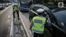 Anggota Kepolisian Korps Lalu lintas melakukan penindakan tilang manual kepada pengendara yang nekat melintasi jalur busway di Jakarta, Selasa (16/5/2023). (Liputan6.com/Faizal Fanani)