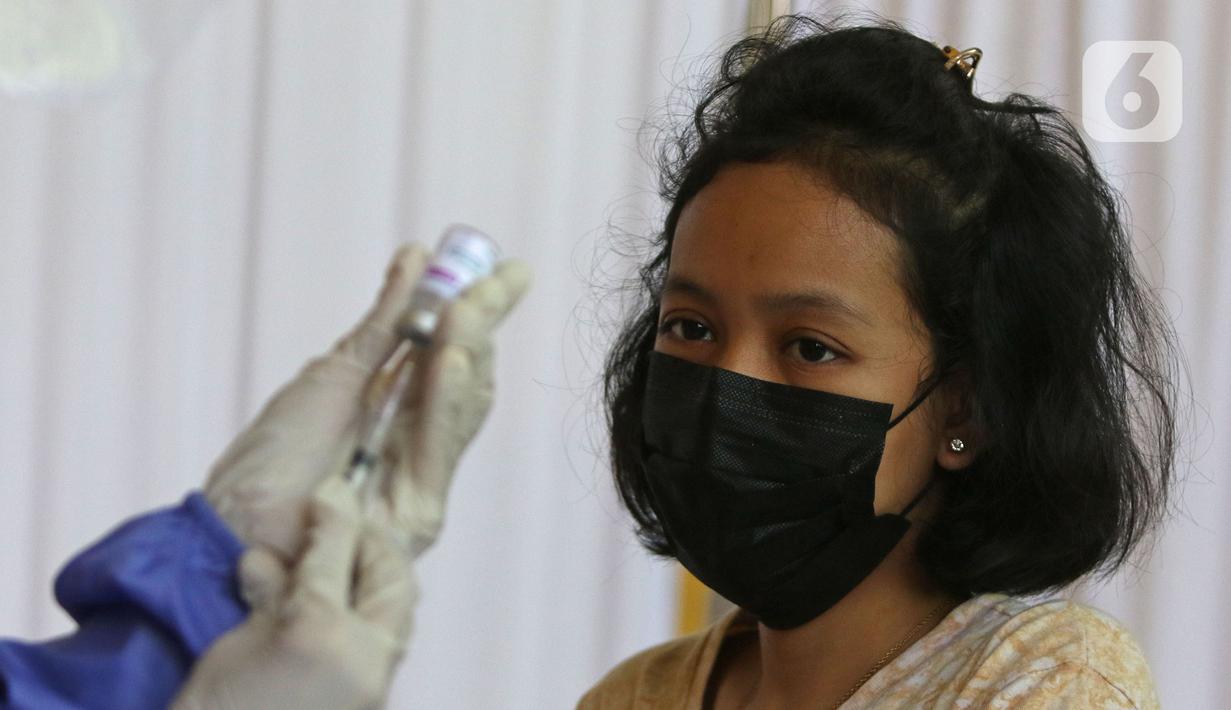 Ekspresi seorang warga sebelum divaksin di MTs As-Syafiiyah, Cilangkap, Jakarta, Kamis (3/6/2021). Vaksinasi massal bagi warga RT 03/RW 03 Cilangkap, Cipayung, Jakarta Timur menggunakan vaksin produksi AstraZeneca. (Liputan6.com/Herman Zakharia)