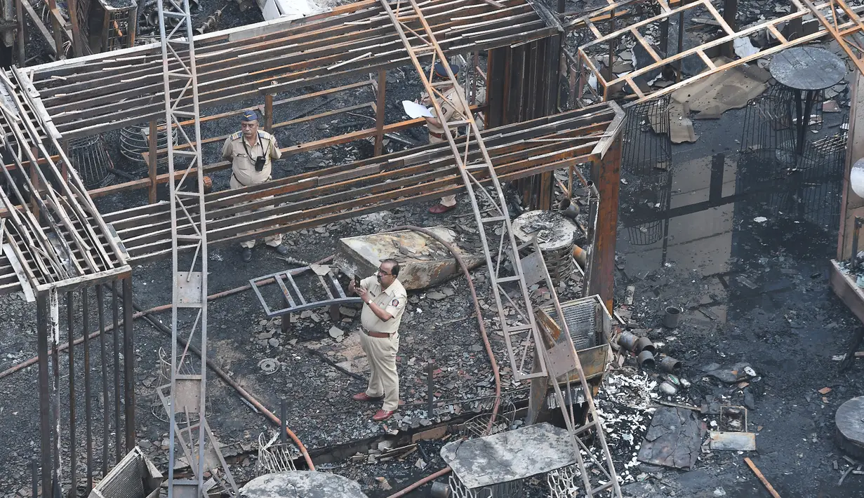 Polisi India menyelidiki sisa-sisa bangunan yang hangus terbakar di sebuah restoran di Mumbai, India (29/12). Restoran yang populer di India tersebut ludes terbakar dan mengakibatkan 15 orang tewas. (29/12 (AFP Photo/Indranil Mukhrejee)