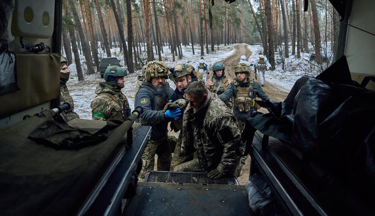 Petugas medis militer membantu tentara yang terluka ke dalam kendaraan evakuasi dekat Kremenna di wilayah Luhansk, Ukraina, 16 Januari 2023. Hingga saat ini pejabat Ukraina menolak untuk mengonfirmasi jumlah korban dalam perangnya dengan Rusia, setelah ketua Komisi Uni Eropa pada akhir November 2022 lalu memperkirakan bahwa "lebih dari 20.000 warga sipil dan 100.000 tentara Ukraina telah tewas di Ukraina hingga saat ini." (AP Photo/LIBKOS)