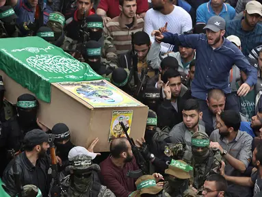 Tentara Hamas mengenakan topeng dan membawa senjata mengiringi peti jenazah enam pejuang mereka yang tewas di Deir el-Balah, Jalur Gaza (6/5). Sebelumnya telah terjadi ledakan yang menewaskan enam pejuang Hamas pada Sabtu (5/5). (AP/Khalil Hamra)