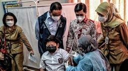Gunernur DKI Jakarta Anies Baswedan (kedua kiri) melihat seorang murid disuntik vaksin COVID-19 saat meninjau hari pertama pelaksanaan vaksinasi COVID-19 untuk anak 6-11 tahun di SDN Cempaka Putih Timur 03 Pagi, Jakarta, Selasa (14/12/2021). (merdeka.com/Iqbal S. Nugroho)
