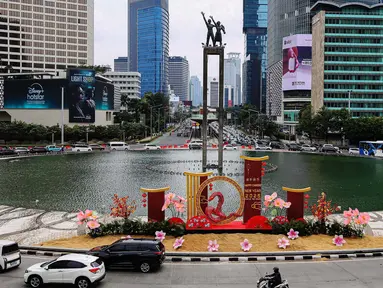 Sejumlah pengendara kendaran bermotor melintasi dekorasi ornamen khas perayaan Imlek di Bundaran Hotel Indonesia, Jakarta, Senin (27/1/2025). (Liputan6.com/Angga Yuniar)