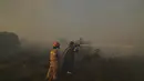 Petugas pemadam kebakaran menyemprotkan air di Gunung Penteli, Selasa (19/7/2022). Pejabat Dinas Pemadam Kebakaran mengatakan 11 pesawat pemadam kebakaran dan lima helikopter dikerahkan untuk mencoba dan menghentikan api mencapai lebih dalam ke daerah-daerah yang dihuni di lereng Gunung Penteli. (AP Photo/Thanassis Stavrakis)