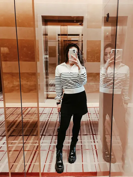 Ibu satu anak ini juga tampil mengenakan atasan lengan panjang putih bergaris hitam, dipadukan mini skirt dan celana warna hitam cocok dengan bootsnya. (@nikitawillyofficial94)