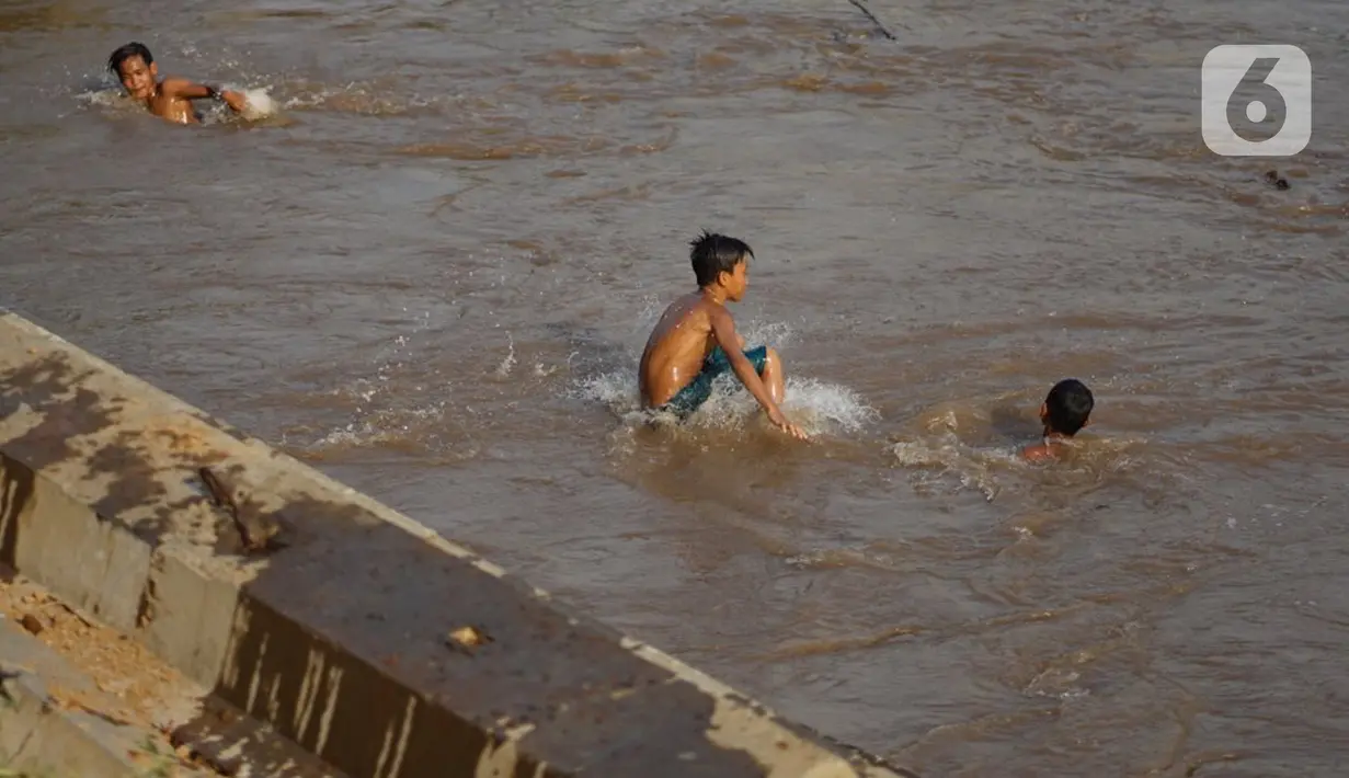 Anak-anak berenang di bantaran Sungai Ciliwung, Jakarta, Senin (5/10/2020). Derasnya aliran Sungai Ciliwung akibat hujan deras yang mengguyur Jakarta tidak menyurutkan kemauan anak-anak tersebut untuk tetap berenang, meski dapat membahayakan keselamatan mereka. (Liputan6.com/Immanuel Antonius)