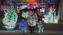 Pengunjung memakai masker saat mengunjungi dekorasi lampu di sebuah mal di Beijing, Jumat, 30 Desember 2022. China berada di jalan terjal untuk kembali ke kehidupan normal ketika warganya kembali ke sekolah, pusat perbelanjaan, dan restoran setelah berakhirnya kebijakan pembatasan paling parah di dunia diakhiri secara tiba-tiba, bahkan ketika rumah sakit dibanjiri pasien Covid-19 yang demam dan meriang parah. (AP Photo/Ng Han Guan)