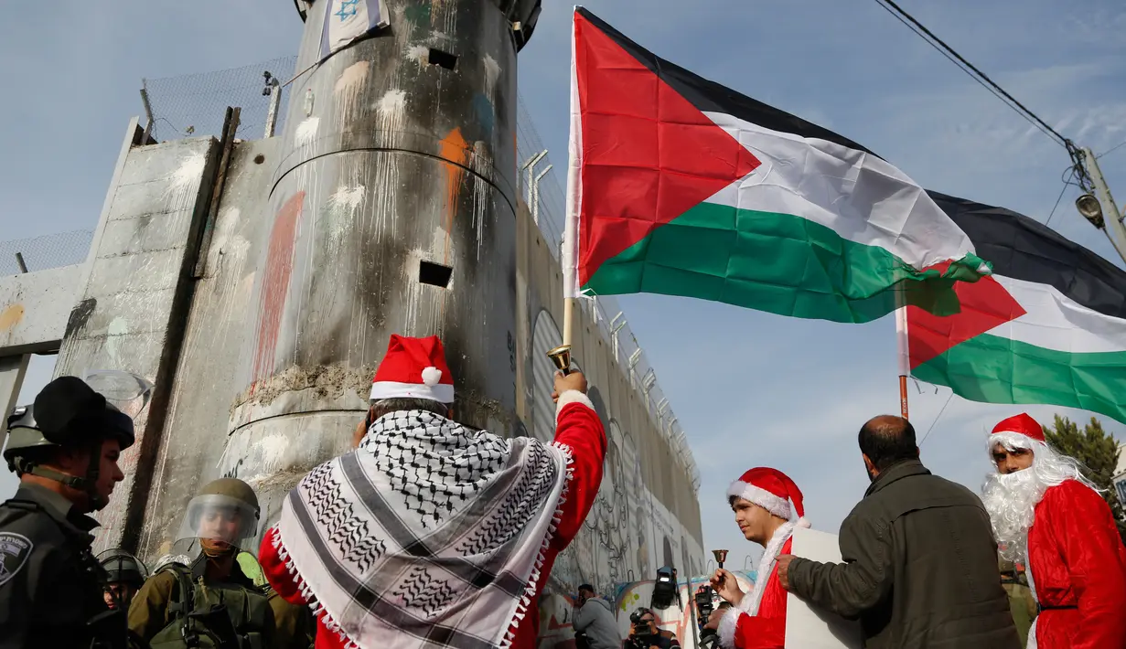 Pengunjuk rasa berkostum sinterklas (Santa Claus) berhadapan dengan polisi perbatasan Israel dalam demonstrasi di Bethlehem, Tepi Barat, 23 Desember 2017. Protes terkait pengakuan Donald Trump atas Yerusalem sebagai Ibu Kota Israel. (AP/Nasser Shiyoukhi)