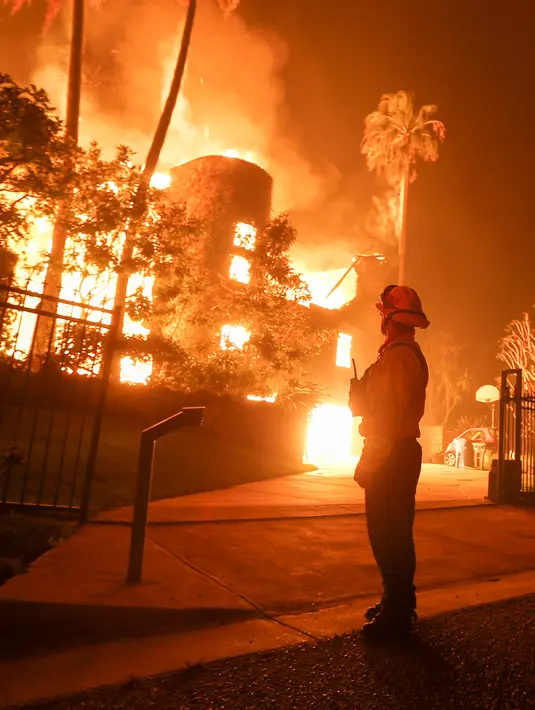 Seorang petugas pemadam kebakaran mengawasi kobaran api yang membakar sebuah rumah di Malibu, California, AS, Jumat (9/11). Api telah melahap 5.665 hektare. (AP Photo/Ringo H.W. Chiu)
