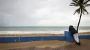 Seorang pria berdiri di dekat pantai sebelum kedatangan Badai Tropis Fiona di San Juan, Puerto Rico, Sabtu (17/9/2022). Fiona diperkirakan akan menjadi badai saat mendekati Puerto Rico dan akan melintasi wilayah teritori Amerika Serikat pada Minggu pagi. (AP Photo/Alejandro Granadillo)