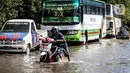 Kendaraan bermotor melintasi jalan yang tergenang air rob (banjir pasang air laut) di Kawasan Pasar Ikan Muara Baru, Jakarta, Kamis (4/6/2020). Banjir rob di Pelabuhan Muara Baru tersebut terjadi akibat cuaca ekstrem serta pasangnya air laut. (Liputan6.com/Faizal Fanani)