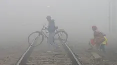 Keluarga menyebrangi jalur kereta api saat kabut tebal di Jalandhar (25/12). India Utara dilanda kabut pagi yang pekat dalam beberapa hari terakhir saat suhu dingin dan kondisi angin rendah turun di wilayah tersebut. (AFP Photo/Shammi Mehra)