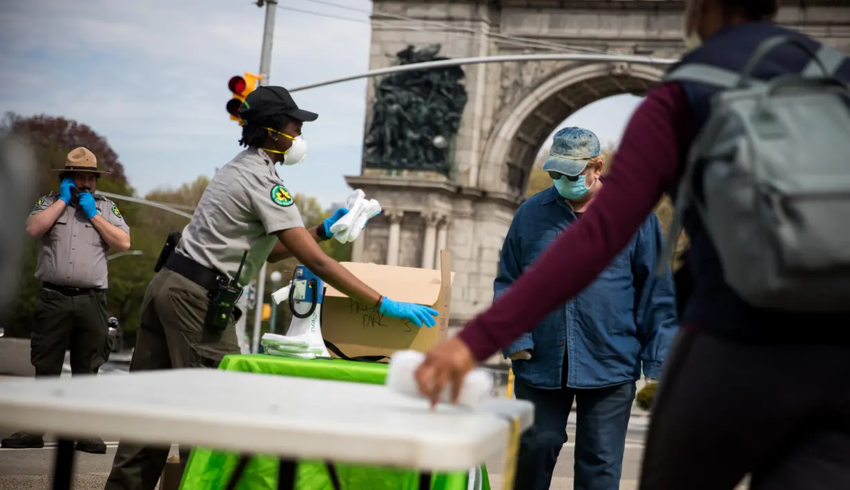 Petugas jagawana taman kota New York City membagikan masker gratis di Prospect Park di wilayah Brooklyn di New York, Amerika Serikat (3/5/2020). Menurut panduan dari Departemen Kesehatan NYC, semua warga New York diwajibkan mengenakan masker atau penutup wajah. (Xinhua/Michael Nagle)