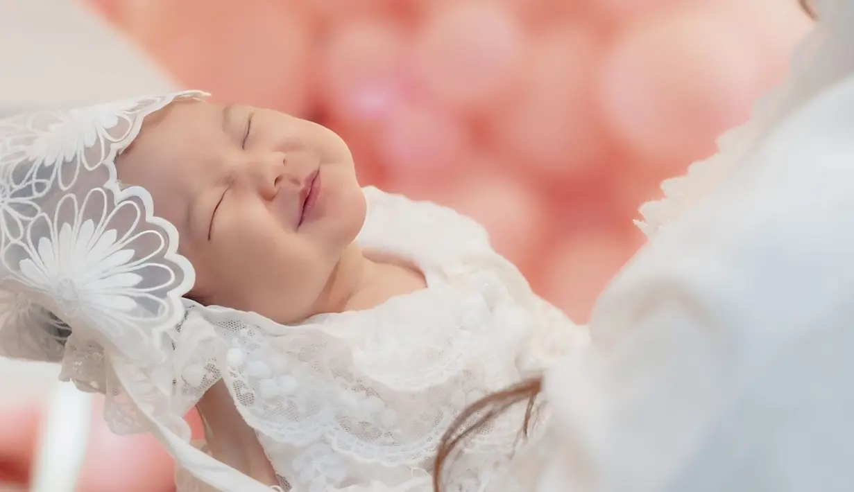 Fotografer tak sengaja memotret, Baby Kimova yang pamer senyuman manis sampai matanya ikut tersenyum ketika sedang tidur ini dipuji cantik oleh netizen. Pake baju putih lengkap dengan jilbab mininya, Baby Kimova semakin gemas. Tak sedikit netizen berkomentar dan menyebut jika foto tersebut adalah foto favorit dari sederet foto momen akikah Baby Kimova. (Liputan6.com/IG/@vicymelanie)