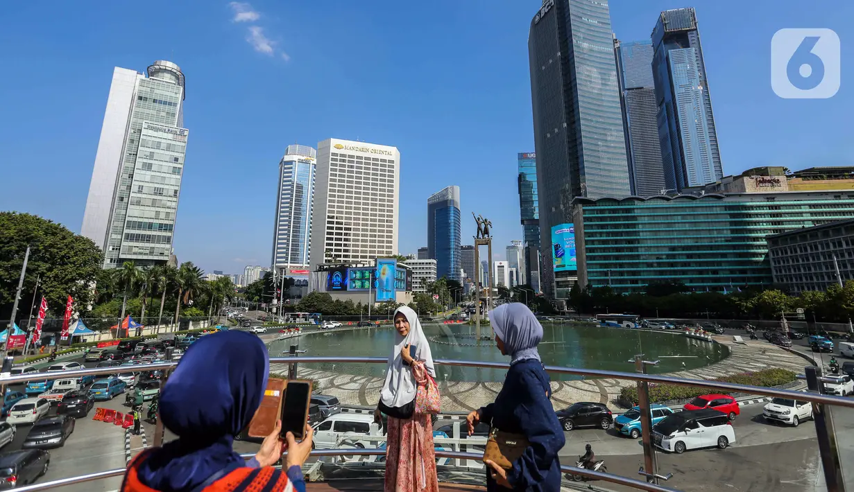 Sejumlah orang berswafoto di anjungan Transjakarta kawasan Bundaran HI, Jakarta, Selasa (1/8/2023). Menurut Badan Meteorologi, Klimatologi, dan Geofisika (BMKG) suhu udara akan berkisar 22 hingga 34 derajat Celcius di siang hari, dengan kelembaban 50-80 persen. (Liputan6.com/Faizal Fanani)