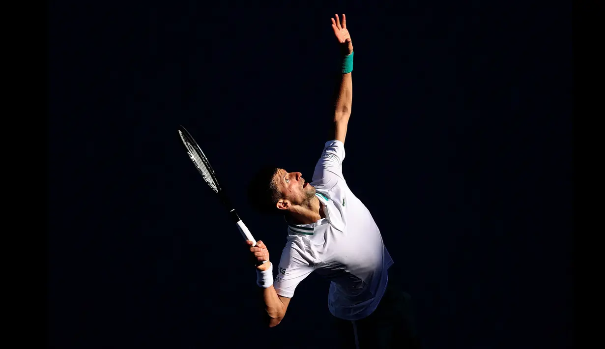 Petenis peringkat satu dunia, Novak Djokovic melakukan servis kearah Frances Tiafoe dalam ajang Australian Open. Novak Djokovic memenangkan perlombaan tersebut dengan susah payah. (Foto: AFP/David Gray)
