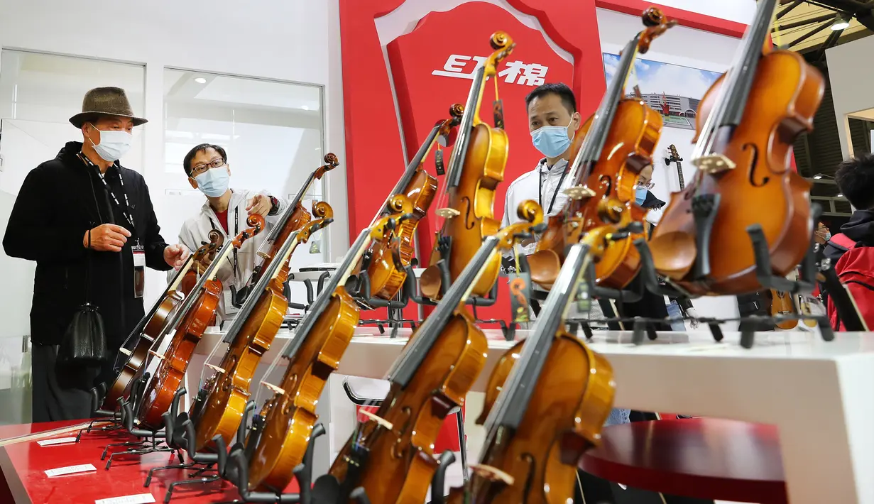 Seorang staf (kedua dari kiri) memperkenalkan biola kepada pengunjung pada ajang Music China 2020 di Shanghai New International Expo Center, China, 28 Oktober 2020. Music China 2020 diikuti lebih dari 1.000 industri musik dari 11 negara dan kawasan dengan produk-produk baru mereka. (Xinhua/Fang Zhe)