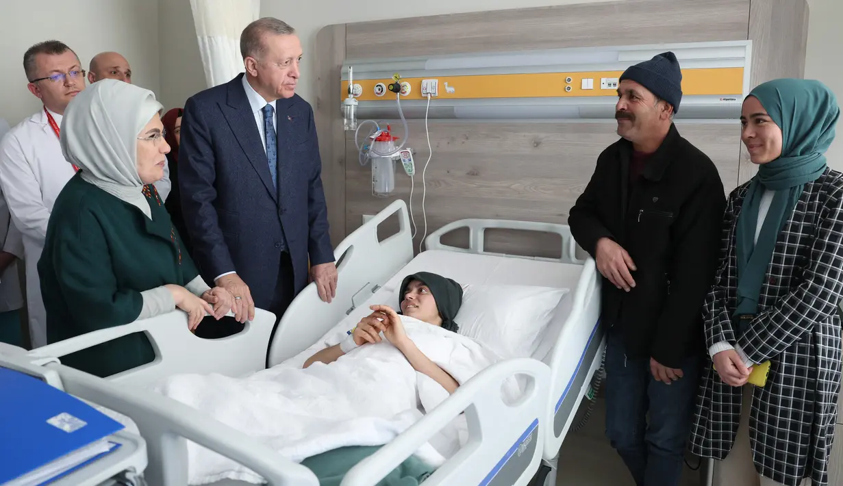 Gambar selebaran yang dirilis pada 22 Februari 2023 menunjukkan Presiden Turki Recep Tayyip Erdogan (kiri ke-2) dan istrinya Emine Erdogan (kiri) mengunjungi anak korban gempa yang menerima perawatan di Fakultas Kedokteran Universitas Ankara setelah dipindahkan dari daerah yang dilanda gempa di Turki. Presiden Erdogan menjanjikan akan menghidupkan kembali daerah terdampak gempa Turki dalam jangka waktu setahun. (Press Office of the Presidency of Turkey / AFP)
