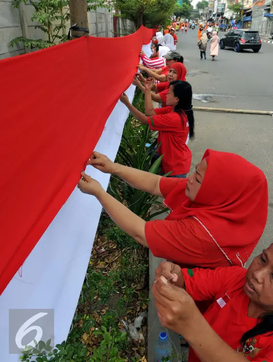 Sejumlah warga tampak serius menjahit bendera merah putih saat mengikuti lomba di Kelurahan Pekojan, Jakarta, Minggu (16/8/2015). Sebanyak 700 ibu-ibu mengikuti lomba menjahit bendera Merah Putih sepanjang 500 meter. (Liputan6.com/Panji Diksana)