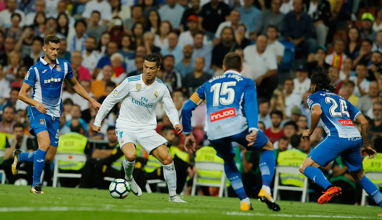 Pemain Real Madrid, Cristiano Ronaldo berusaha menendang bola dengan kawalan pemain Espanyol dalam lanjutan La Liga 2017/2018 di Santiago Bernabeu, Minggu (1/10). Real Madrid sukses menundukkan Espanyol dua gol tanpa balas. (AP/Paul White)
