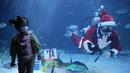 Seorang gadis melihat penyelam yang mengenakan pakaian Sinterklas pada acara untuk mempromosikan liburan Natal di Coex Aquarium, Seoul, Korea Selatan, Jumat (3/12/2021). Natal adalah salah satu hari libur terbesar yang dirayakan di Korea Selatan. (AP Photo/Ahn Young-joon)