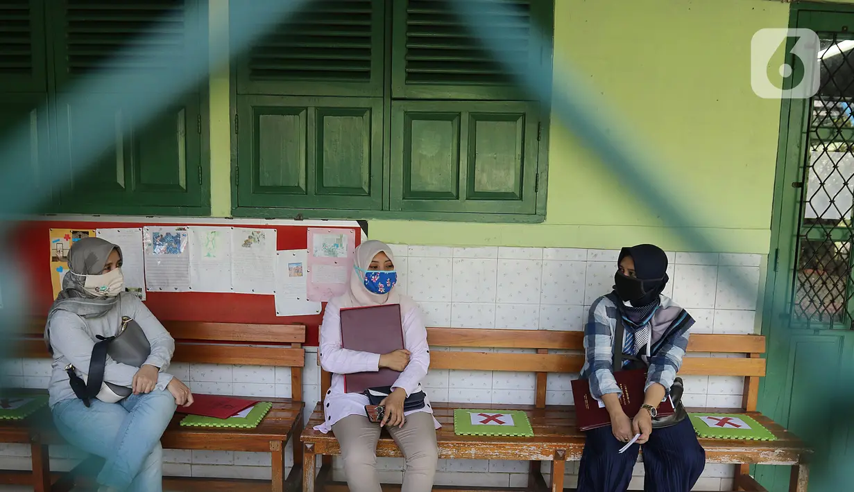 Wali murid duduk sambal berbincang seusai pembagian laporan hasil belajar (rapor) kenaikan kelas di SD Negeri Menteng 01 Jakarta, Kamis (25/6/2020). Pembagian dilaksanakan mengikuti protokol kesehatan COVID-19 serta membagikan rapor secara bertahap dari 24-26 Juni 2020 (Liputan6.com/Herman Zakharia)