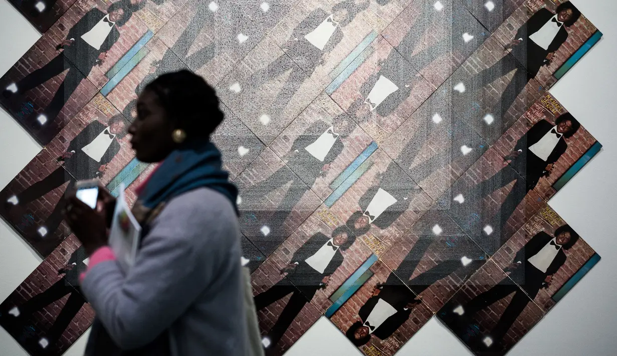 Pengunjung melewati karya seni Graham Dolphin dalam pameran Michael Jackson: On The Wall di museum Grand Palais, Paris, Rabu (21/11). Pameran ini menyatukan karya-karya lebih dari empat puluh seniman, dalam gaya yang sangat berbeda. (Philippe LOPEZ/AFP)