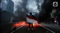 Pendemo foto di kobaran api saat aksi unjuk rasa di kawasan patung kuda, Jakarta, Selasa (20/10/2020). Gelombang protes tolak UU Cipta Kerja belum surut sejak disahkan pada 5 Oktober lalu. (Liputan6.com/Johan Tallo)