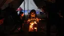 Mereka bertahan melawan dingin malam dengan membuat api unggun. (Omar AL-QATTAA/AFP)