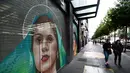 Pejalan kaki melintasi mural yang dilukis di pintu toko wilayah bersejarah Mexico City, Meksiko, 30 Agustus 2017. Mural menjadi salah satu langkah Pemerintah Mexico City untuk melestarikan dan mempercantik ruang publik. (ALFREDO ESTRELLA/AFP)