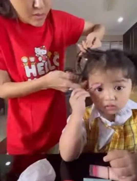 Sambil rambutnya dikunciri sang ibunda, Thania Putri Onsu asyik menggambar alisnya dengan pensil khusus. (Foto: Instagram/@sarwendah29)