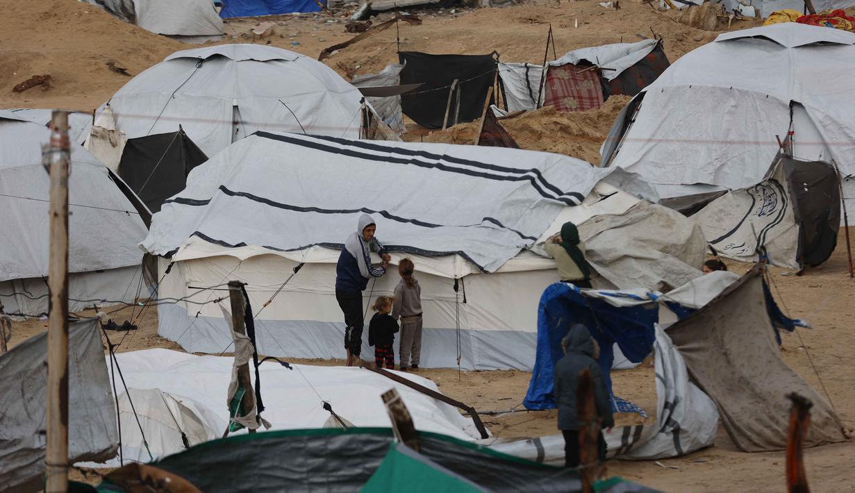 Kepala Kantor Media Pemerintah di Gaza, Ismail Thawabta, mengonfirmasi dari sekitar 135.000 tenda yang tersebar di kamp-kamp pengungsian, 127.000 di antaranya tidak memenuhi standar kelayakan. Tampak dalam foto, seorang pria Palestina yang mengungsi memperbaiki tenda yang didirikan di sepanjang pantai Kota Gaza saat angin musim dingin yang kencang menerpa wilayah tersebut pada Selasa 13 Januari 2026. (Omar AL-QATTAA/AFP)