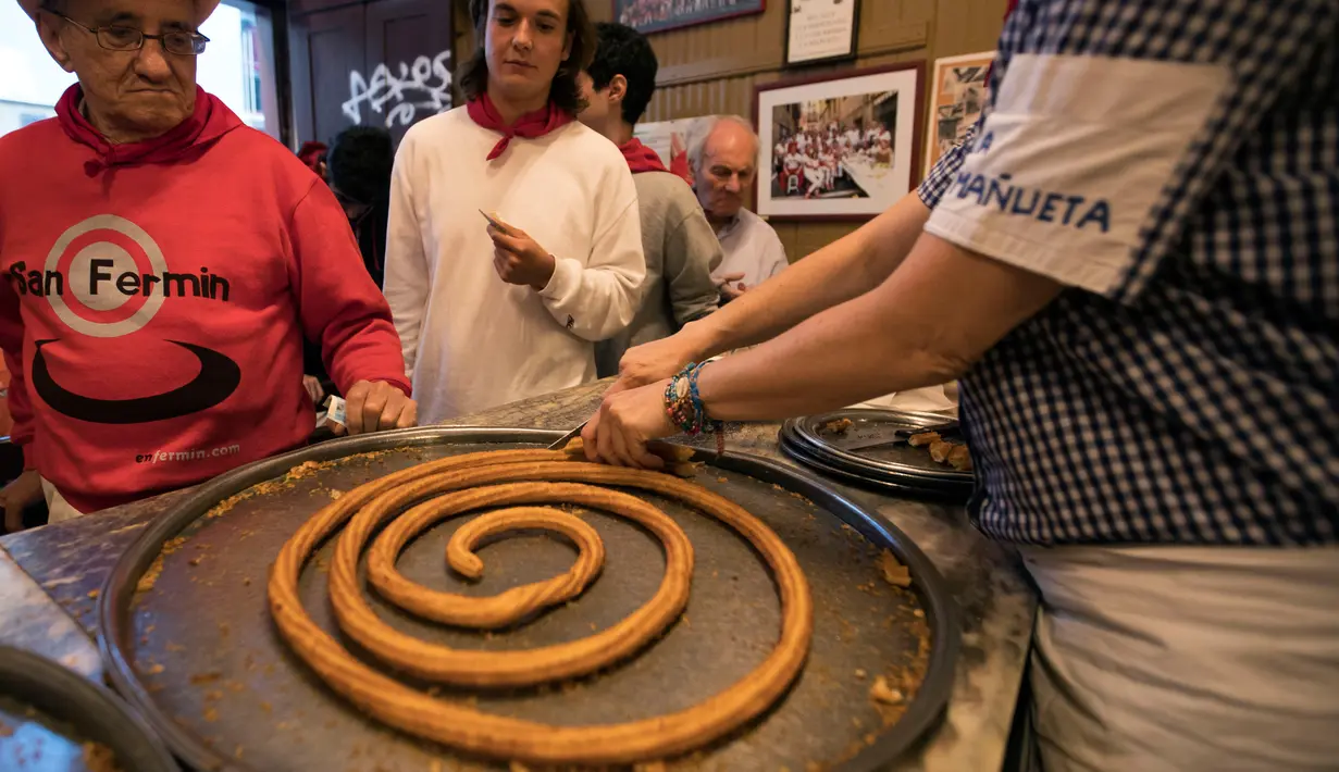 Karyawan memotong-motong donat khas Spanyol atau churros di restoran dessert tradisional La Manueta, Pamplona, Spanyol, Rabu (10/7/2019). Jika dulu hanya dikenal dengan rasa manis setelah digoreng, saat ini churros memiliki topping yang lebih beraneka ragam. (JAIME REINA/AFP)