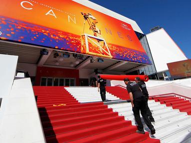 Pekerja memasang karpet merah di depan pintu masuk utama jelang upacara pembukaan Festival Film Cannes 2019 di Cannes, Prancis, Selasa (14/5/2019). Festival Film Cannes merupakan ajang paling bergengsi di dunia perfilman. (REUTERS/Regis Duvignau)