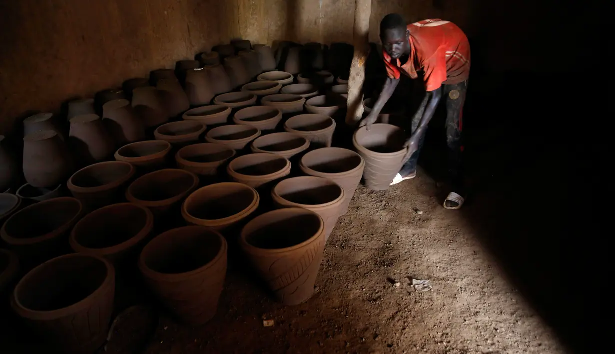 Pekerja mengeringkan pot tanah liat sebelum memajangnya untuk dijual di bengkel tembikar di Khartoum, Sudan, Kamis (27/6/2019). (AP Photo/Hussein Malla)
