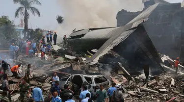 Sejumlah Petugas berusaha melakukan evakuasi pesawat Hercules C-130 yang jatuh di kawasan perumahan di Medan, Selasa (30/6/2015). Hercules C-130 milik TNI AU jatuh tidak lama setelah lepas landas. (AFP PHOTO/Kharisma Tarigan)