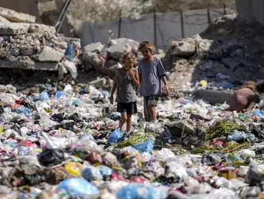 Anak-anak pengungsi memilah-milah sampah di sebuah jalan di Deir al-Balah, Jalur Gaza tengah pada 29 Agustus 2024. (AP Photo/Abdel Kareem Hana)